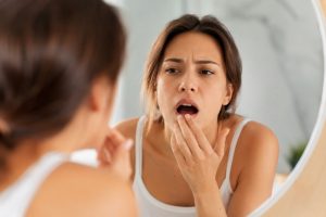 Mujer revisando su boca por sensación de suciedad bucal.